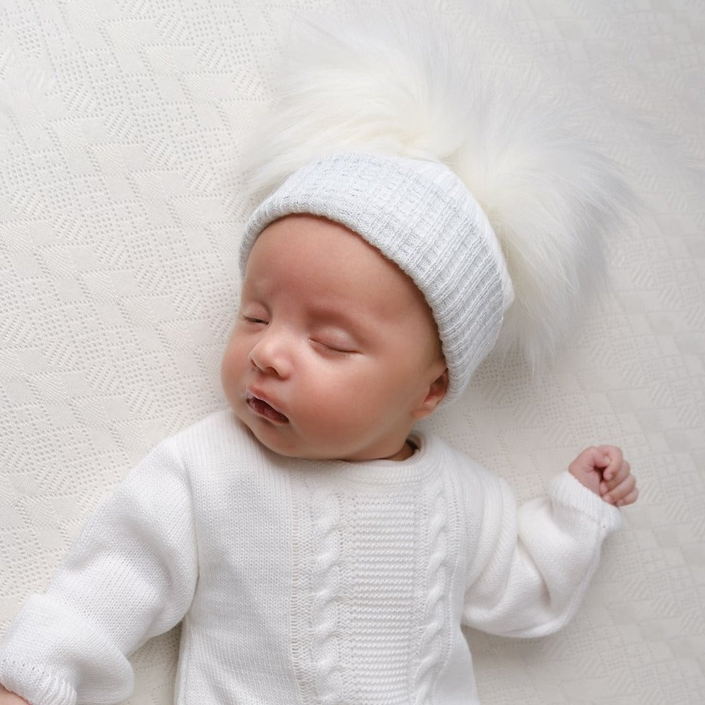 Baby wearing first size white and silver ribbed fur double pom hat