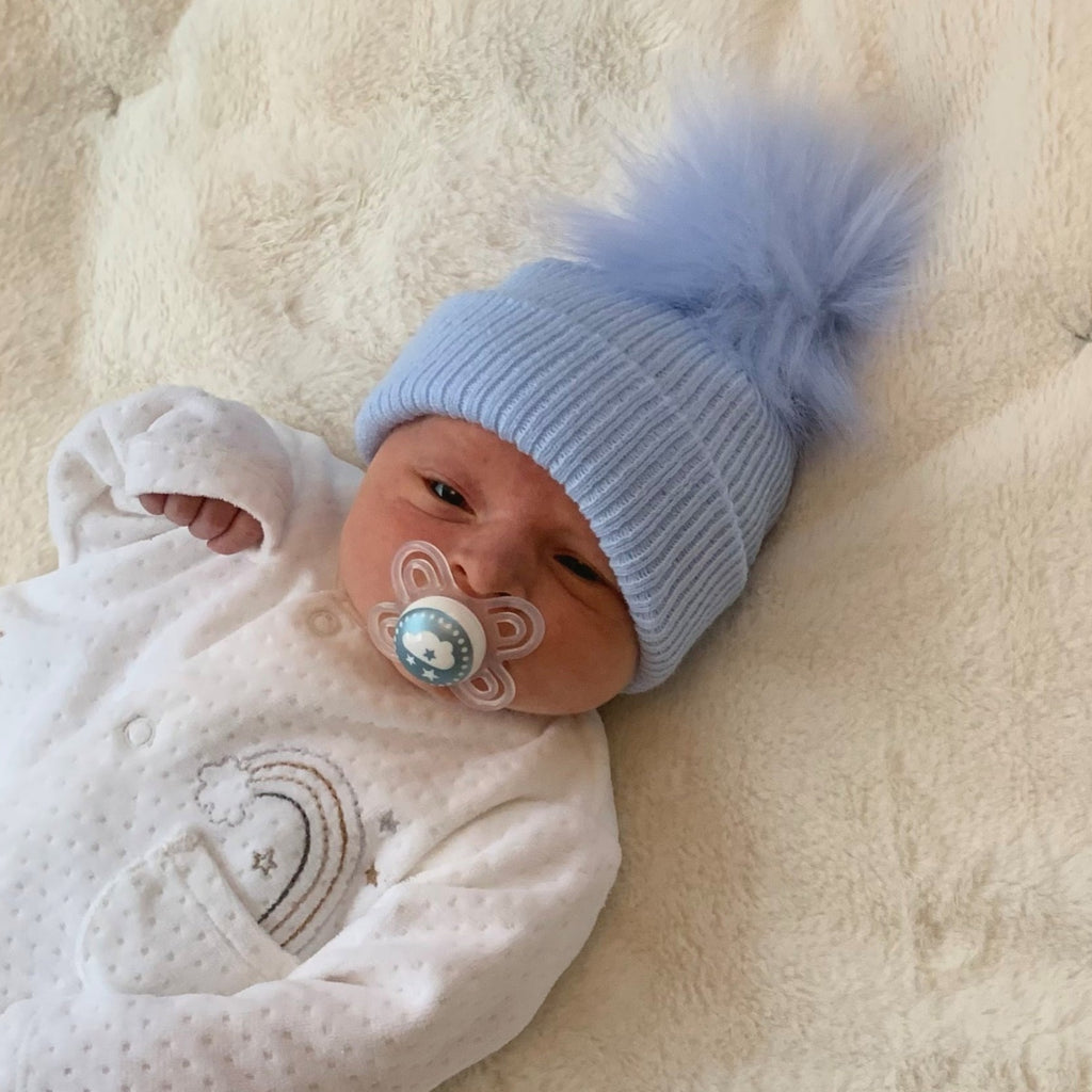 Baby wearing the first size sky blue ribbed fur pom hat