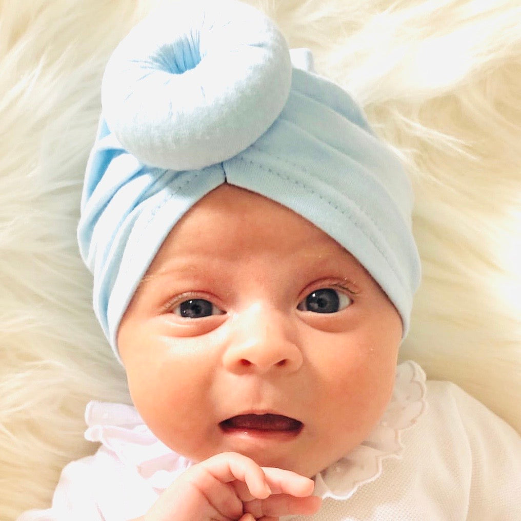 Baby wearing blue donut hat