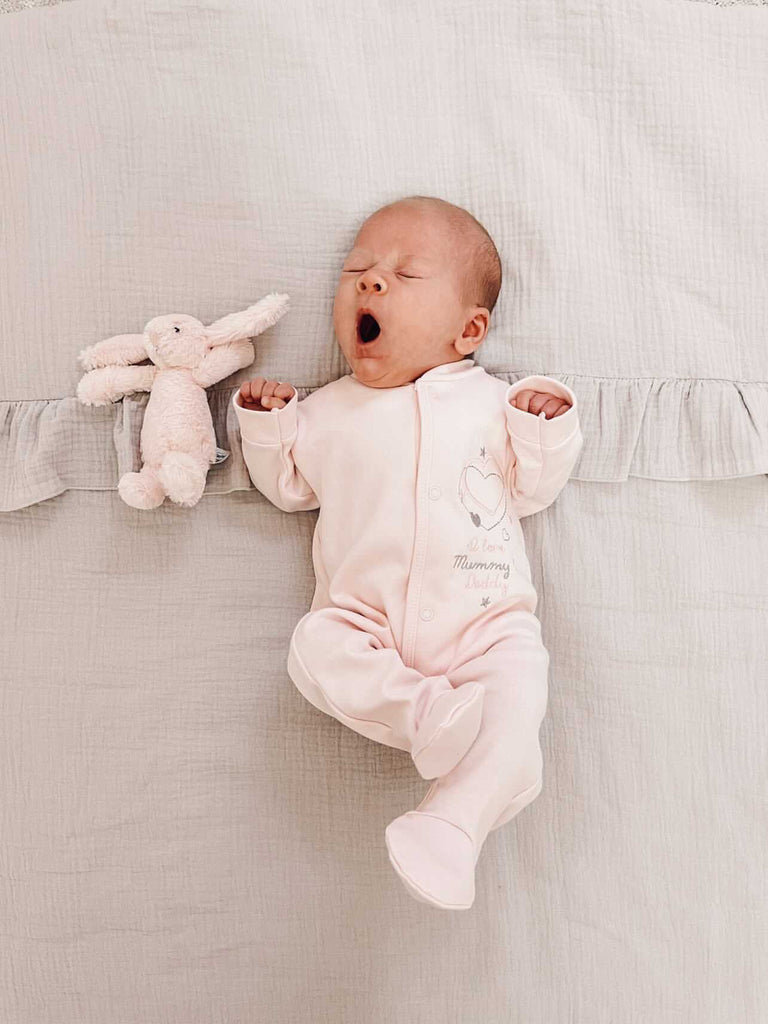 Yawning baby wearing 'I love my Mummy & Daddy' pink cotton sleepsuit