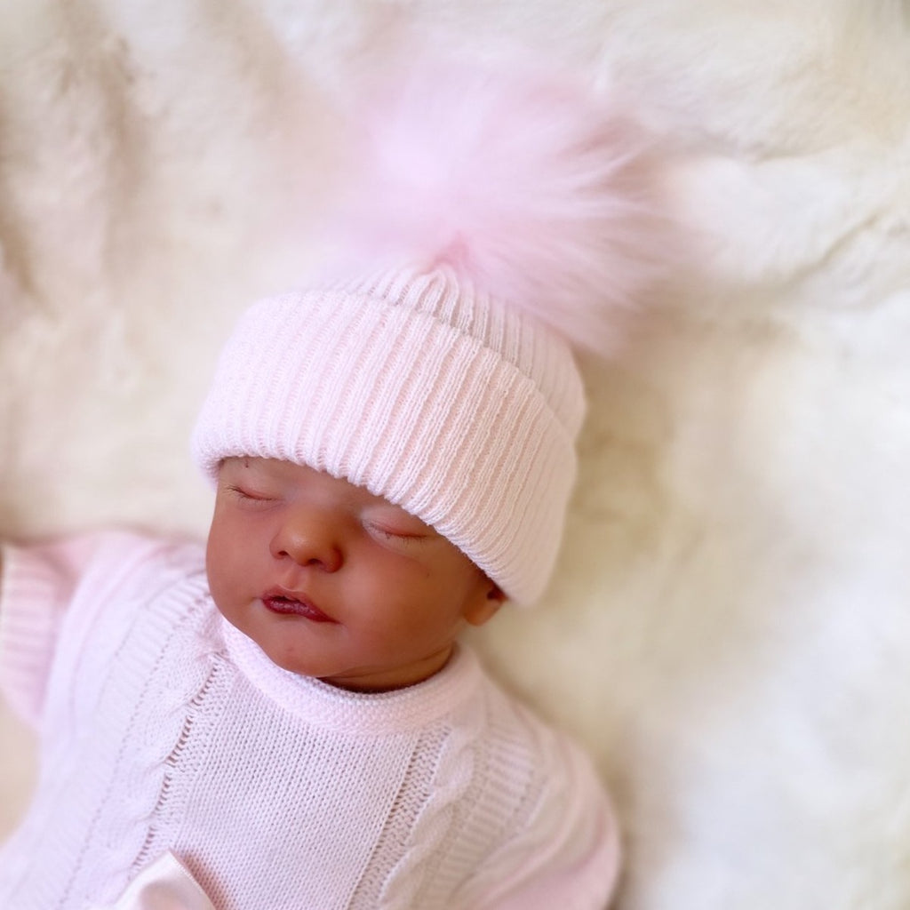 Baby wearing the first size pink ribbed fur pom hat