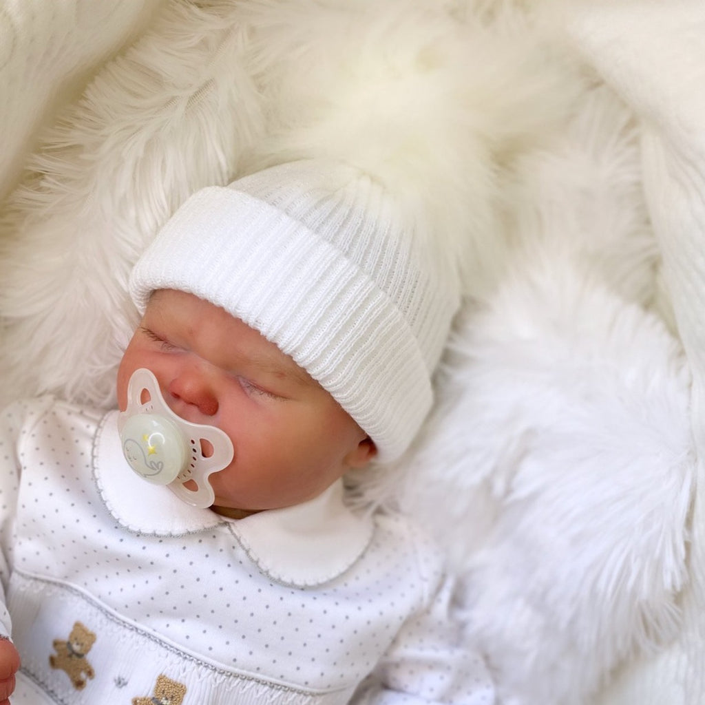 Baby wearing first size white ribbed fur pom hat