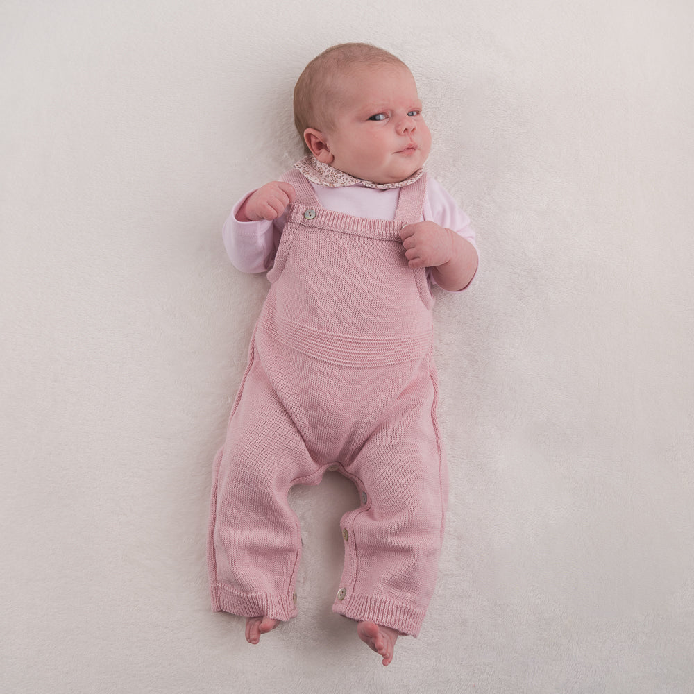 Baby on white background wearing the dusty pink knitted romper