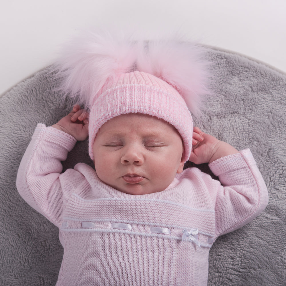Baby wearing first size pink ribbed fur double pom hat