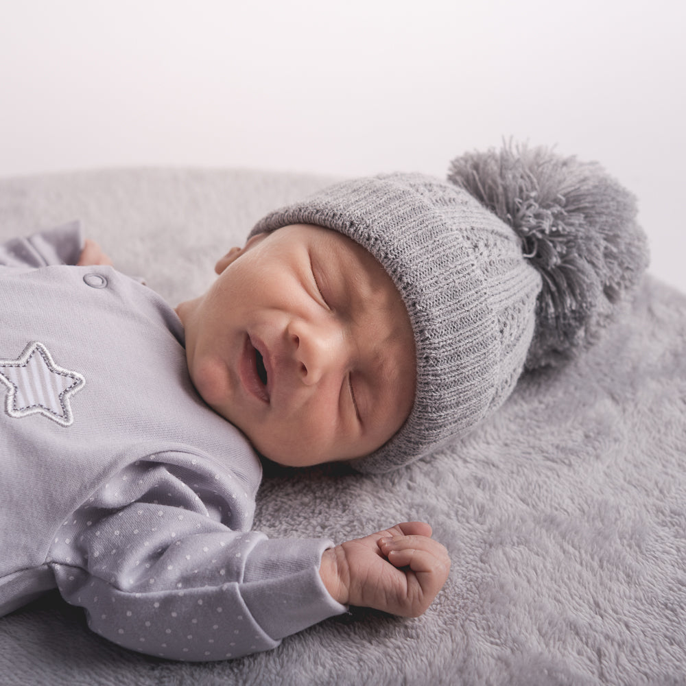 Baby wearing the first size grey cable pom hat