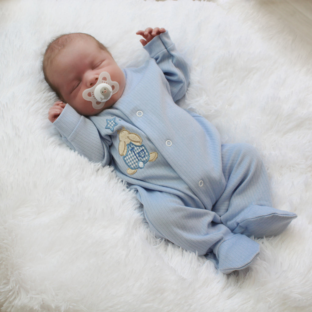 Baby wearing blue rabbit and star ribbed sleepsuit