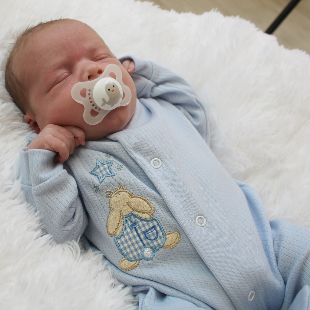 Sleeping baby with dummy wearing the Blue Rabbit & Star Ribbed Sleepsuit