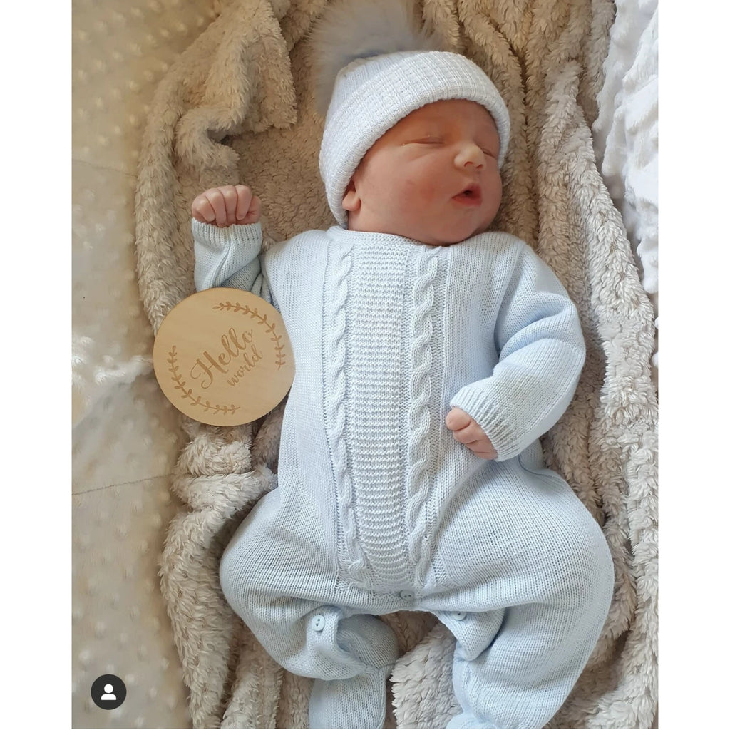 Sleeping baby with hello world sign wearing blue cable knitted onesie