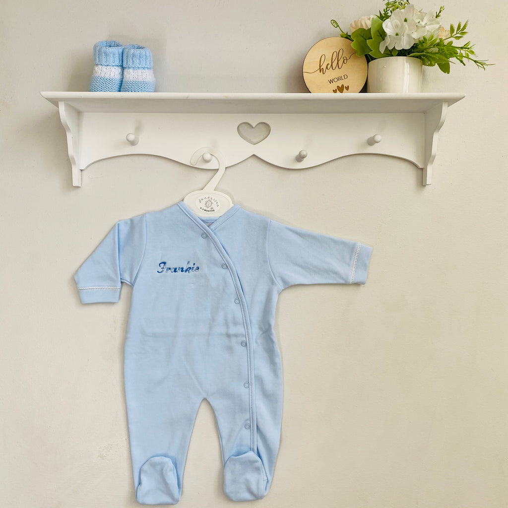 Blue personalised name popper sleepsuit hanging from shelf