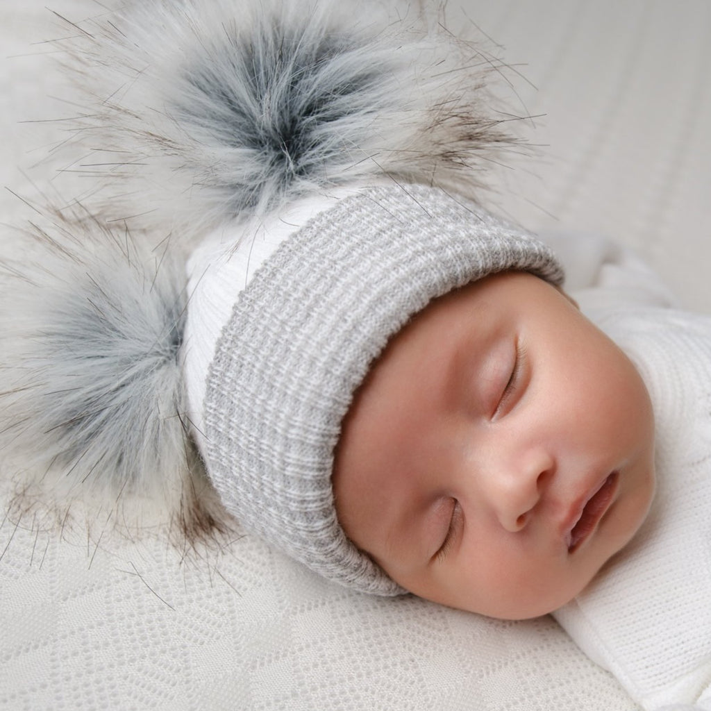 Baby wearing first size white and grey ribbed fur double pom hat
