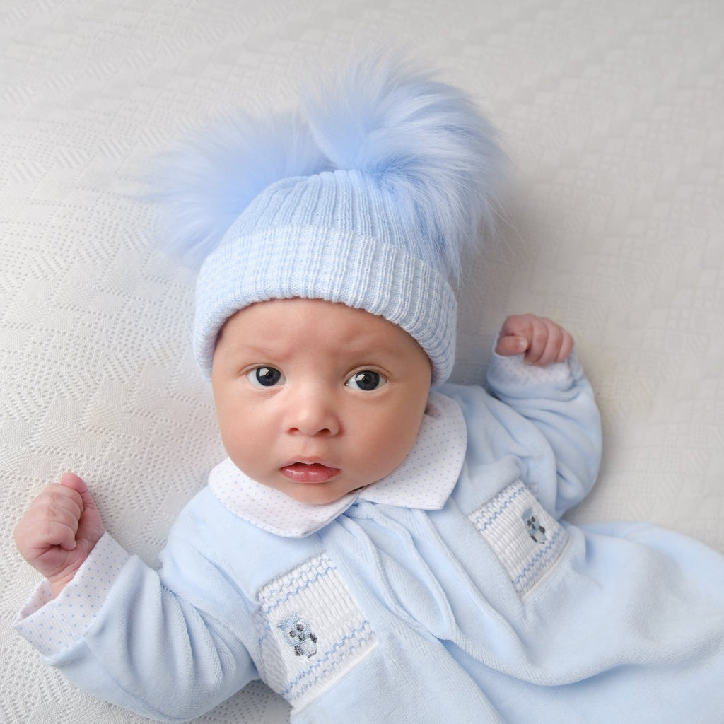 Baby wearing first size blue ribbed fur double pom pom hat