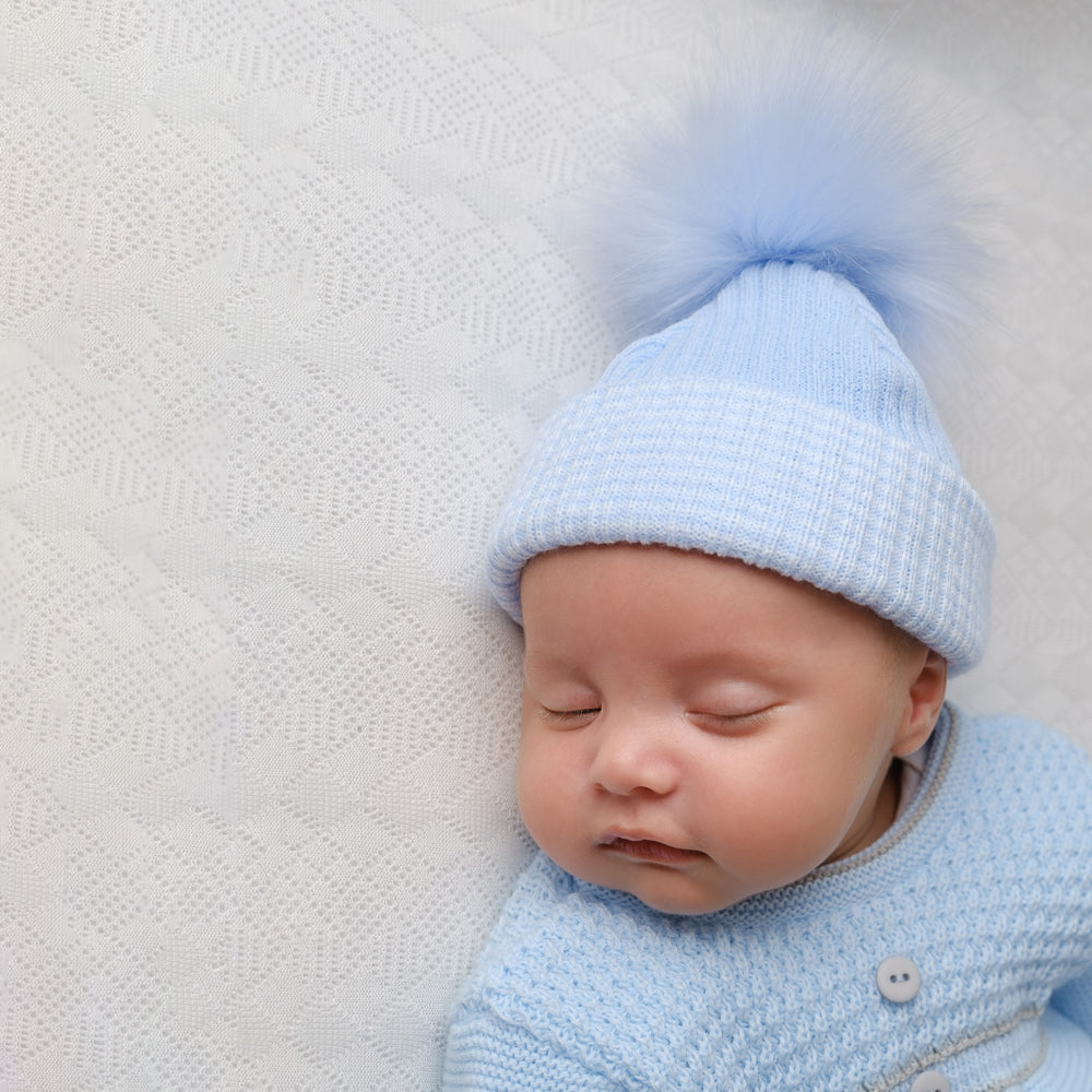 Baby wearing first size blue ribbed fur pom hat