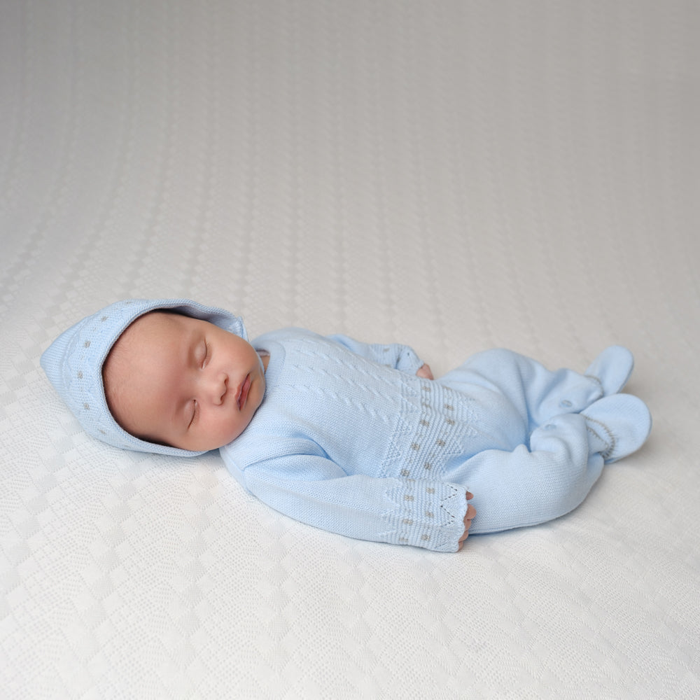 Sleeping baby wearing the blue zig zag knitted onesie and hat