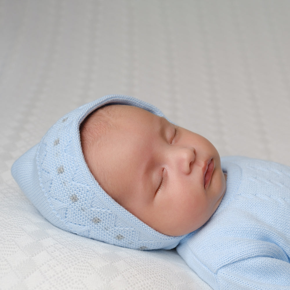 Close up of baby in the hat from the blue zig zag knitted onesie and hat set