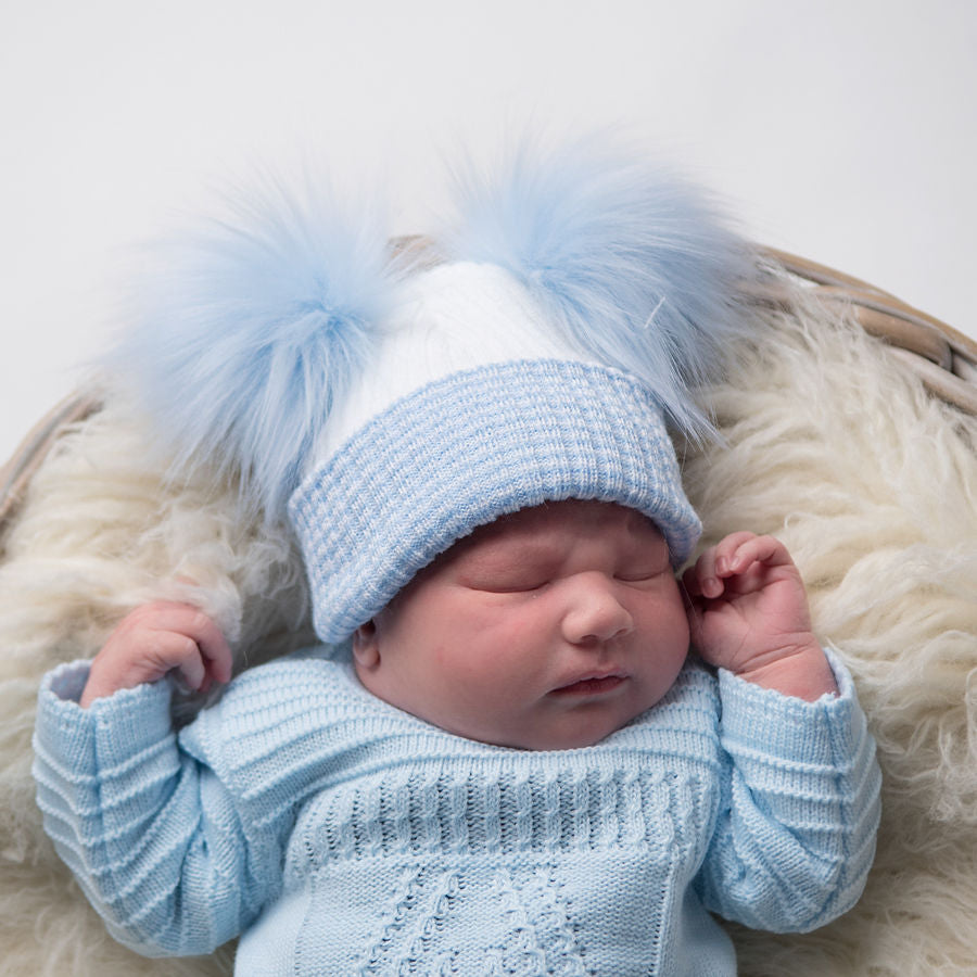 Sleeping baby wearing first size white and blue ribbed fur double pom hat