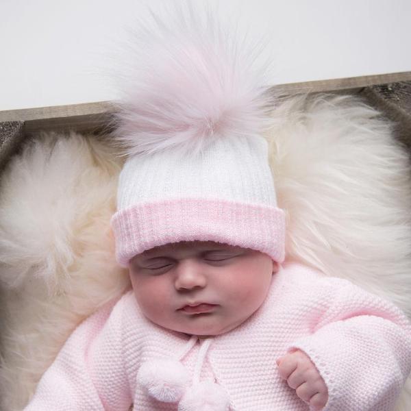 Baby wearing first size white and pink ribbed fur pom hat